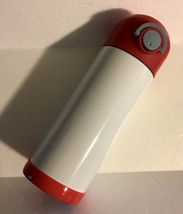 A red and white thermos sitting on top of a table.