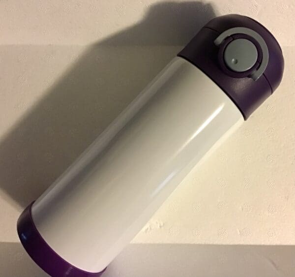 A purple and white thermos sitting on top of a table.