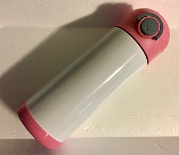 A pink and white thermos sitting on top of a table.